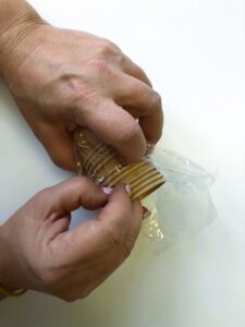 The photo shows a person’s left hand holding a stack of paper cups while the fingers of the right hand are used to count the number of cups in the stack.