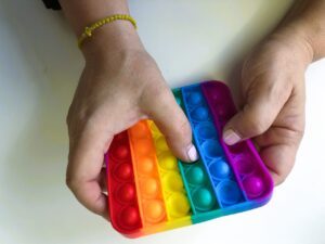 The rainbow-like 6×6 pop-it toy has each row in a different color: red, orange, yellow, green, blue, and lilac.